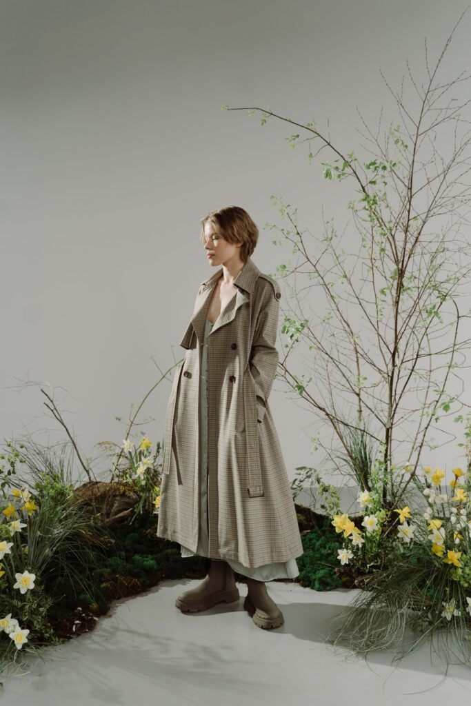 Woman in Brown Coat Standing Beside White Flowers